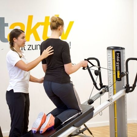Mitarbeiterin unterstützt Patientin am Total Gym GTS Gerät