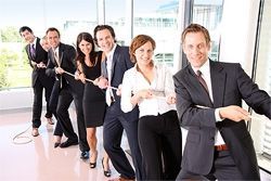 Mehrere Angestellte ziehen gemeinsam an einem Tau und symbolisieren ein starkes Team