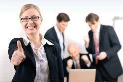 Eine Angestellte steht im Vordergrund des Bildes und zeigt den Daumen nach oben