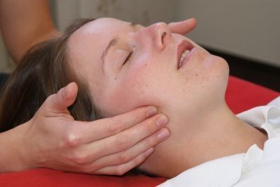 Ein Therapeut führt eine Kiefergelenkstherapie an einer Patientin durch