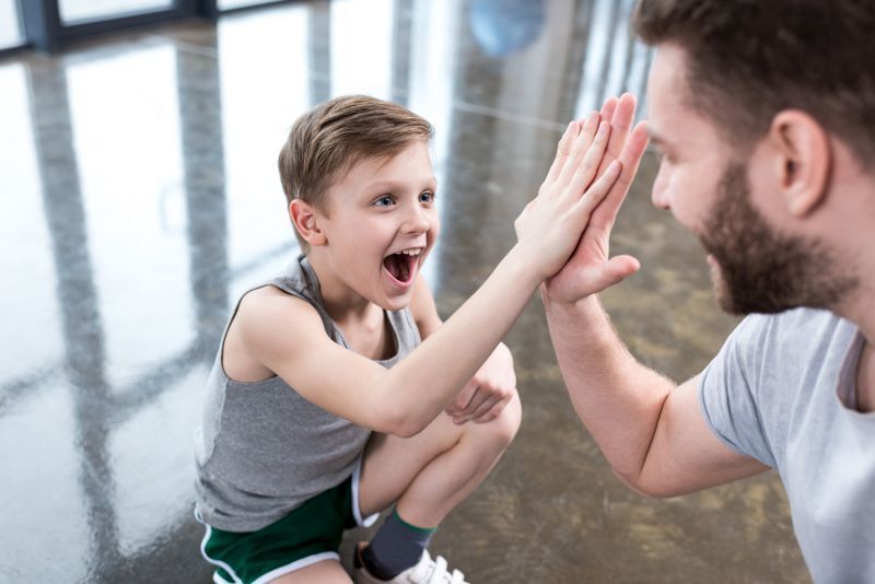 Ein kleiner Junge und sein Trainer geben sich ein High-Five
