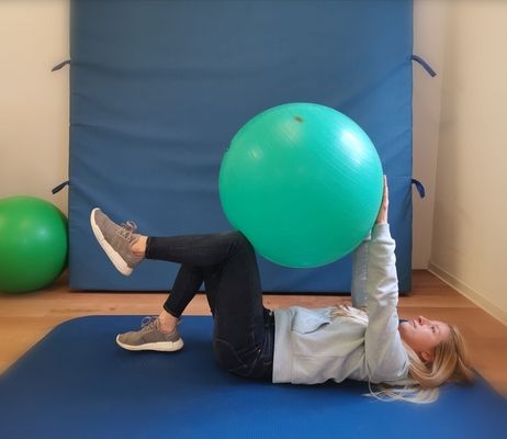 Frau trainiert mit einem Physioball ihren Rücken