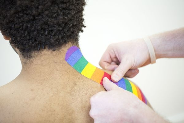 Ein Arzt bringt Kinesiotape am Nacken eines Patienten an