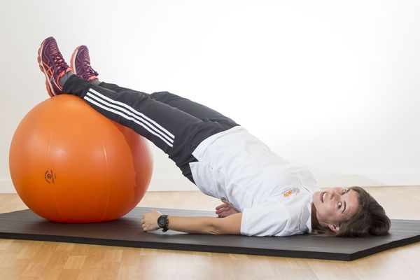 Eine Mitarbeiterin demonstriert Gymnastik mit einem Physioball