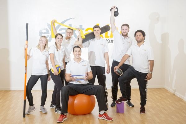 Unser Team der Sporttherapie posiert mit verschiedenen Sportgeräten für ein gemeinsames Foto